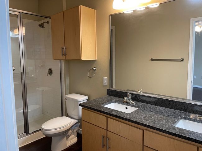 Bathroom featuring double vanity, a stall shower, and wood finished floors | Image 17