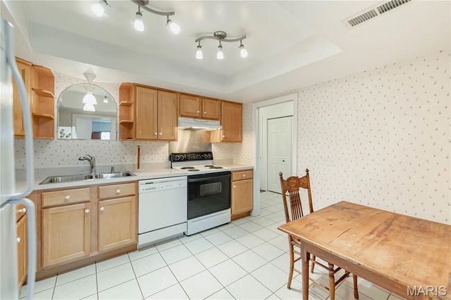 Kitchen featuring white appliances, under cabinet range hood, open shelves, wallpapered walls, and light countertops | Image 21