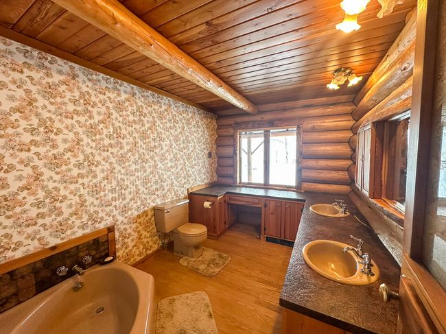 Bathroom featuring toilet, wood-type flooring, wooden ceiling, a bathing tub, and log walls | Image 41