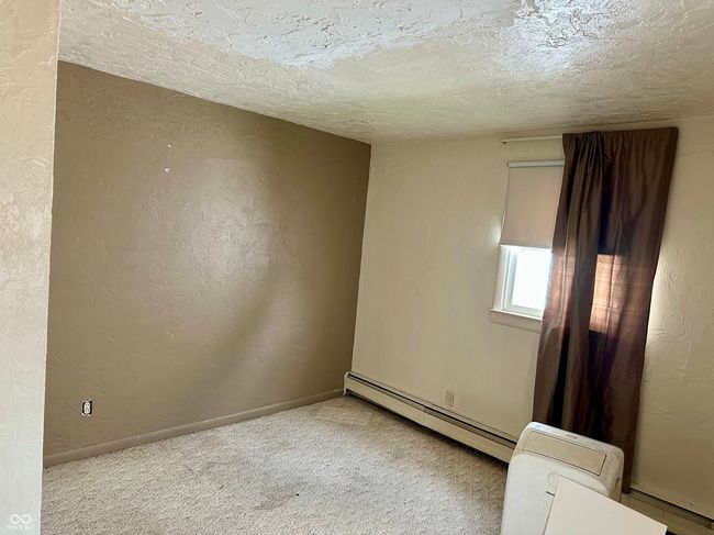 empty room featuring a textured ceiling, baseboards, a baseboard radiator, a textured wall, and carpet flooring | Image 12