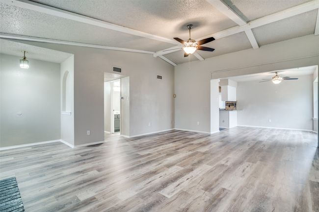 Unfurnished room featuring a ceiling fan, light wood-style floors, a textured ceiling, and arched walkways | Image 6