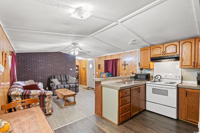 Kitchen featuring electric range, under cabinet range hood, a sink, stainless steel microwave, and a peninsula | Image 12