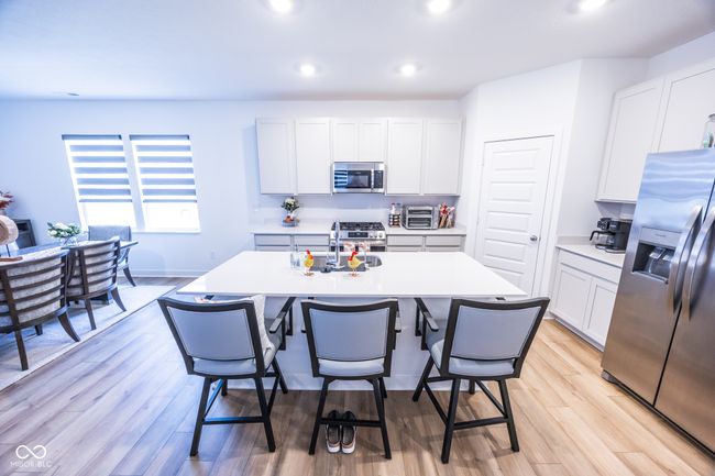 kitchen with appliances with stainless steel finishes, a kitchen island with sink, a breakfast bar area, light countertops, and recessed lighting | Image 7