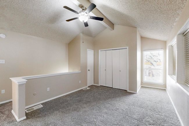 Unfurnished bedroom with visible vents, baseboards, carpet flooring, and vaulted ceiling with beams | Image 29