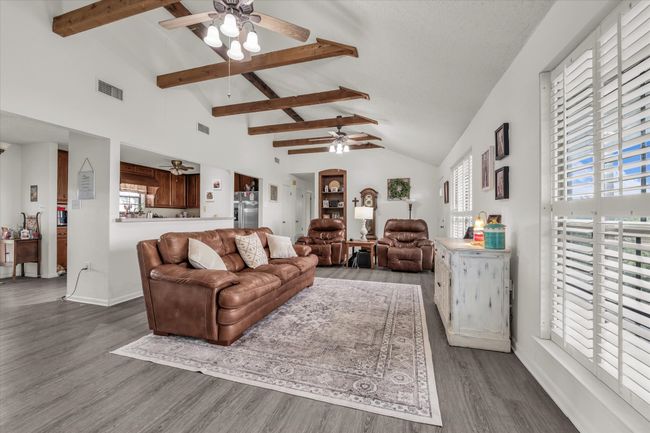 Living room featuring a ceiling fan, wood finished floors, beamed ceiling, and high vaulted ceiling | Image 25