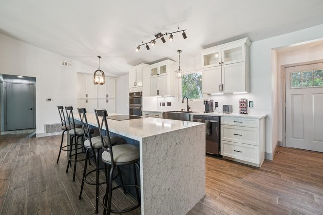 Checf's kitchen with track lighting, waterfall quartz island and breakfast bar | Image 9
