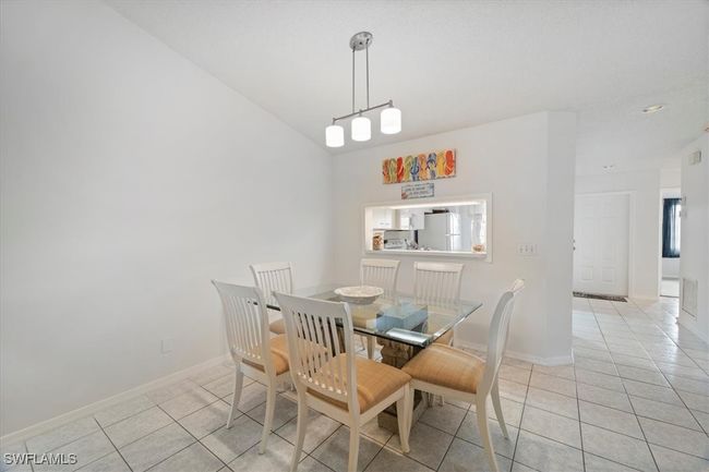 Dining room with light tile patterned floors, baseboards, and lofted ceiling | Image 10