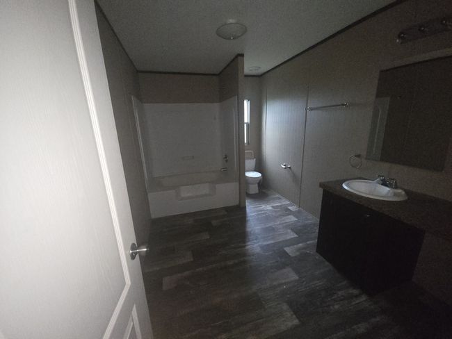 Full bath featuring washtub / shower combination, vanity, toilet, and wood finished floors | Image 18