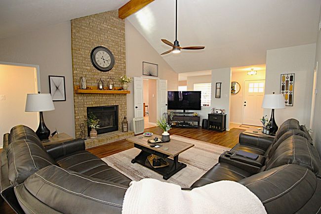 Living area featuring beam ceiling, high vaulted ceiling, a brick fireplace, and ceiling fan | Image 4