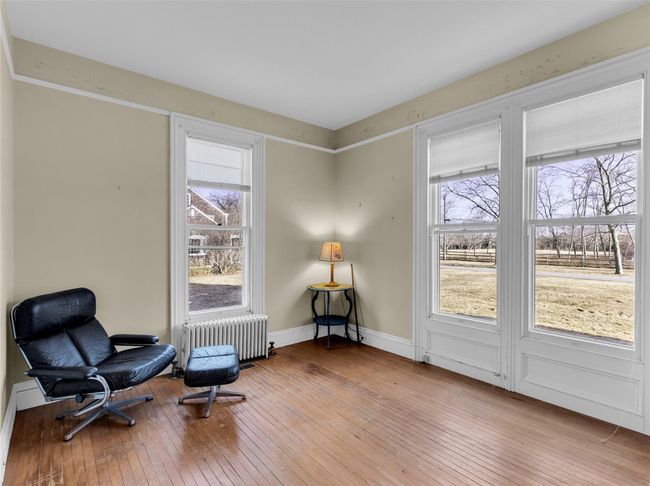 Sitting room with light wood-type flooring, a wealth of natural light, baseboards, and radiator heating unit | Image 16