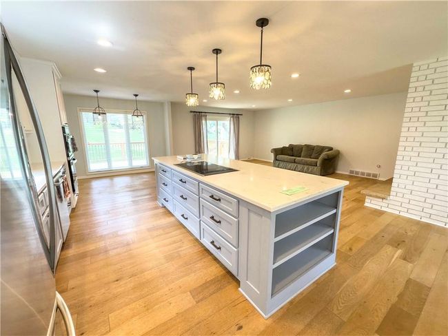 Kitchen featuring freestanding refrigerator, open shelves, visible vents, white cabinets, and black electric cooktop | Image 6