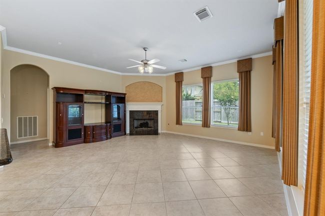 The living room showcases tile floors, crown molding, a cozy gas fireplace, and abundant windows that fill the space with natural light, ceiling fan for an inviting and comfortable atmosphere. | Image 29