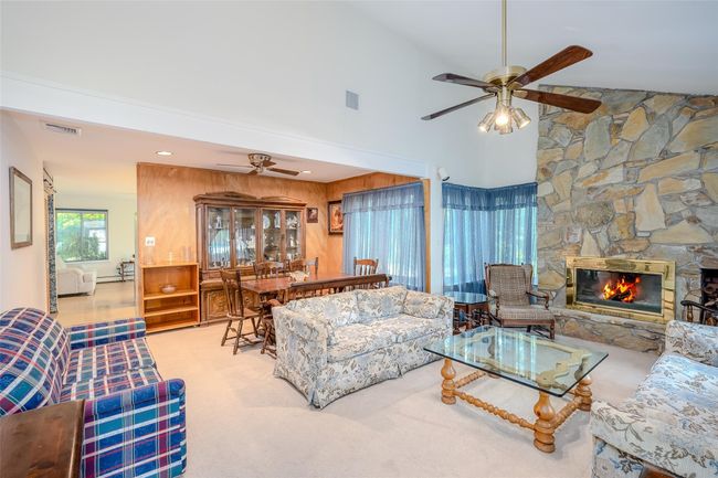 Living room featuring ceiling fan, high vaulted ceiling, a fireplace, and carpet flooring | Image 8