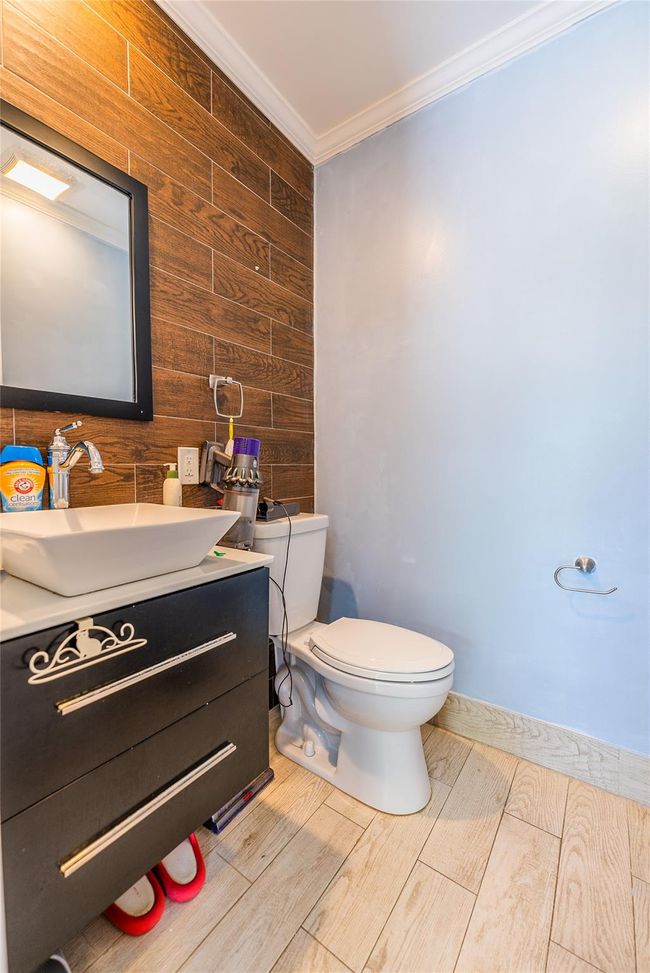 Bathroom featuring wooden walls, toilet, ornamental molding, vanity, and wood finished floors | Image 19