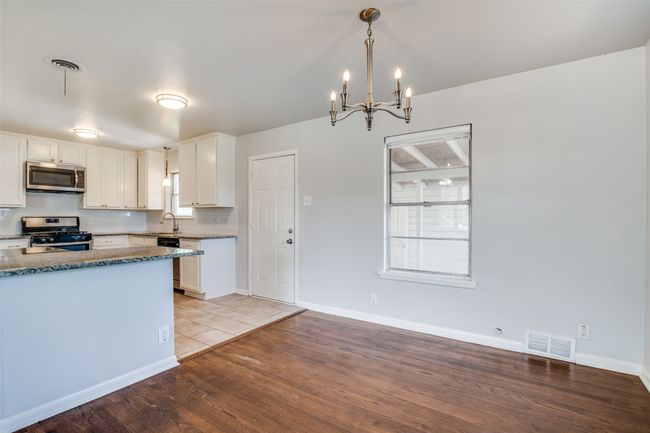 Kitchen featuring a notable chandelier, visible vents, stainless steel appliances, a sink, and wood finished floors | Image 10