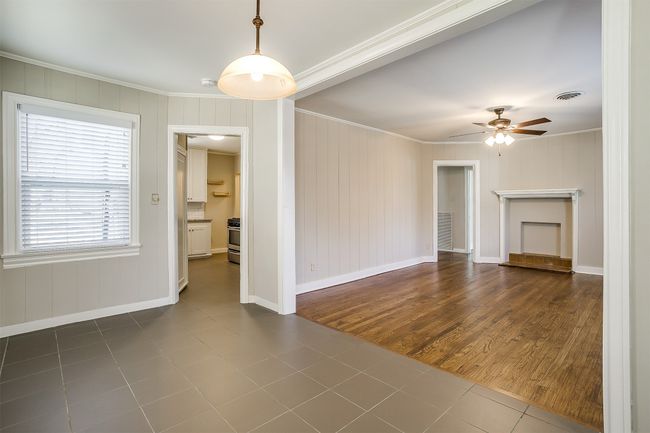 Unfurnished living room with crown molding, a ceiling fan, and dark tile patterned flooring | Image 7