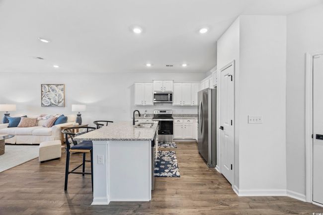 Kitchen featuring open floor plan, a kitchen breakfast bar, dark wood finished floors, a sink, and appliances with stainless steel finishes | Image 6