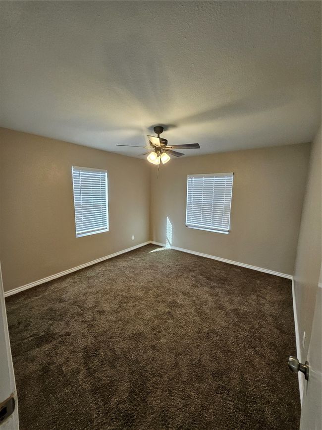 Carpeted empty room with baseboards, a textured ceiling, and ceiling fan | Image 10