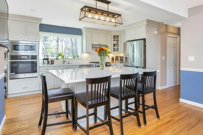 The full kitchen renovation includes an island with Silestone top and countertops, storage cabinets, lighting fixtures, and pretty picture window looking onto rear yard. | Image 4