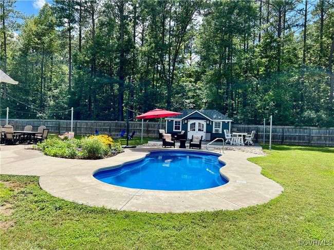 View of swimming pool featuring a pool house , a patio area, a fenced backyard, and outdoor dining area | Image 43