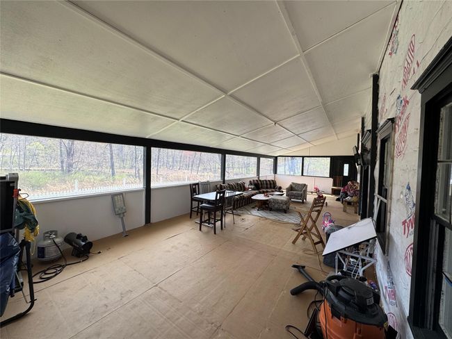 Sunroom / solarium featuring lofted ceiling and an outdoor living space with a fire pit | Image 8
