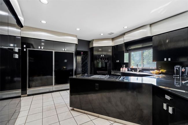 Kitchen with dark cabinets, light tile patterned floors, stovetop with downdraft, and recessed lighting | Image 9