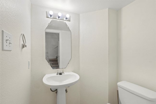 Half bath featuring toilet, a textured wall, and a sink | Image 6
