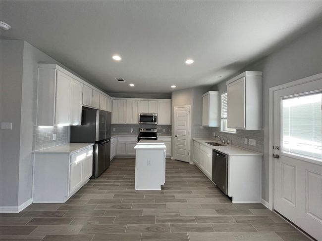 Kitchen featuring stainless steel appliances, decorative backsplash, light countertops, and recessed lighting | Image 6