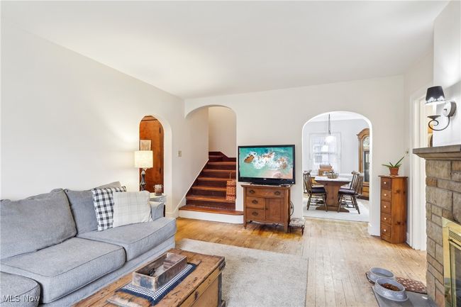 Living area featuring light wood-style flooring, arched walkways, and stairway | Image 7