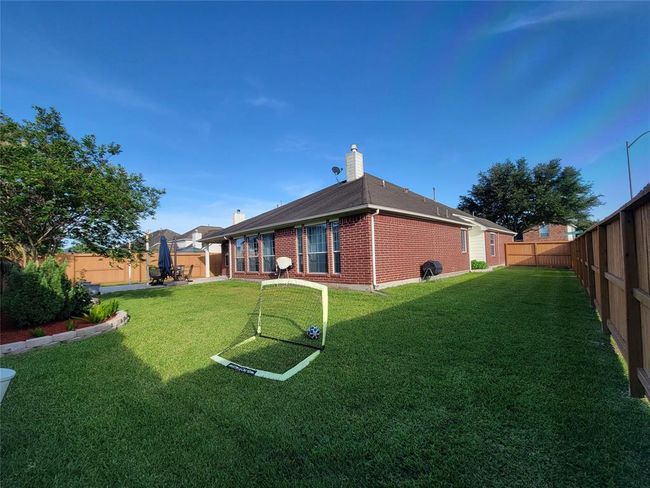 Spacious backyard with well-maintained lawn and patio area, perfect for outdoor activities and relaxation, bordered by a wooden fence for privacy. | Image 31