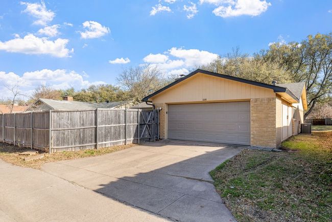 Garage with central AC unit, fence, and concrete driveway | Image 36