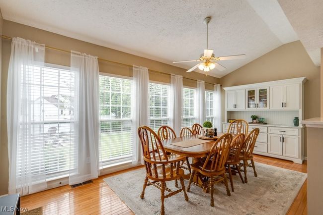 Dining space featuring light wood finished floors, a ceiling fan, lofted ceiling, and a textured ceiling | Image 9