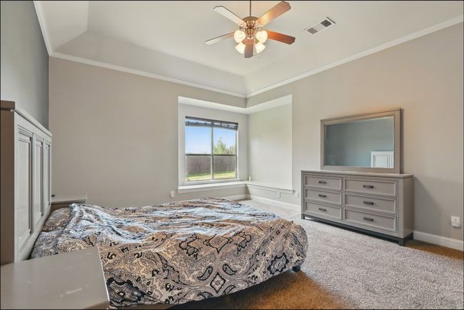 Bedroom featuring a raised ceiling, light carpet, ceiling fan, and ornamental molding | Image 22
