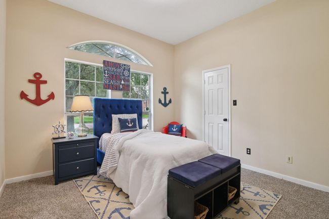 This cozy bedroom features large windows offering natural light. | Image 25