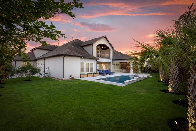 With its expansive green lawn, strategically lit palm trees, and custom heated pool, the space is both elegant and functional with room to play. | Image 41