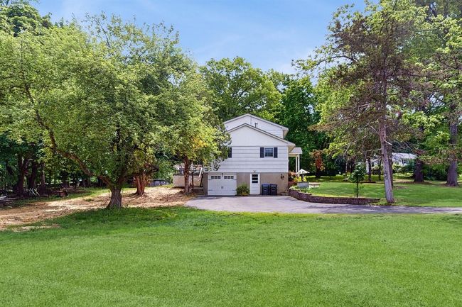 View of lush, green lawn and featuring very long, asphalt driveway. In the background, you'll notice a view of wooded area in the back of the property. | Image 36