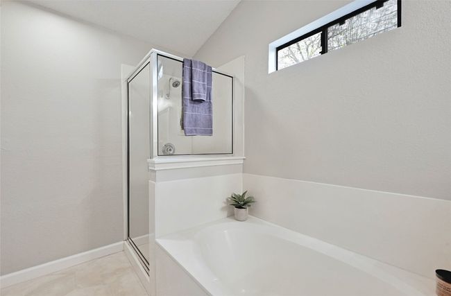 The primary bathroom has a walk-in shower and separate soaking tub and let's in natural light while still allowing for privacy. There is also a walk-in closet accessed in the bathroom. | Image 18