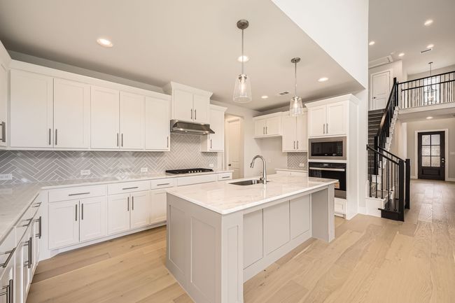Kitchen with black oven, built in microwave, tasteful backsplash, light stone counters, and recessed lighting | Image 12