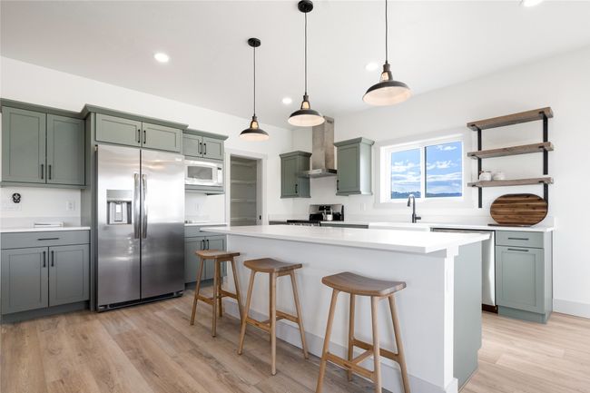 Kitchen with stainless steel fridge, wall chimney exhaust hood, white microwave, stove, and dishwashing machine | Image 15