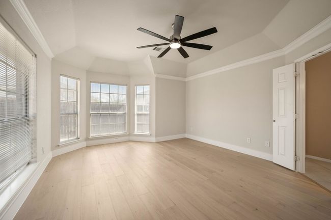Empty room featuring a tray ceiling, a ceiling fan, baseboards, light wood-style floors, and ornamental molding | Image 20