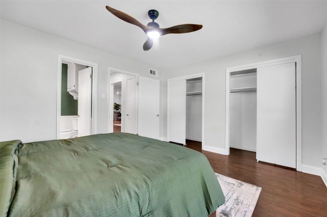 Bedroom featuring two closets, dark wood-style floors, ensuite bath, and a ceiling fan | Image 14
