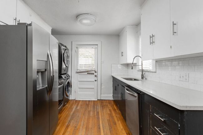 Kitchen with light wood-type flooring, light countertops, stacked washer / drying machine, appliances with stainless steel finishes, and a sink | Image 28