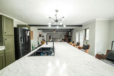 Kitchen with a breakfast bar, a chandelier, black fridge, and sink | Image 3