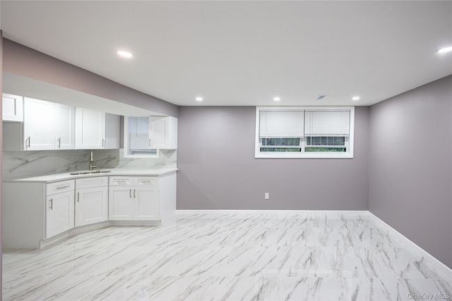 Kitchen featuring decorative backsplash, white cabinetry, recessed lighting, light stone counters, and light marble finish floors | Image 28