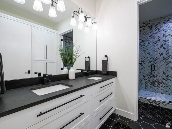Bathroom featuring double vanity, tiled shower, a chandelier, and tile patterned flooring | Image 88