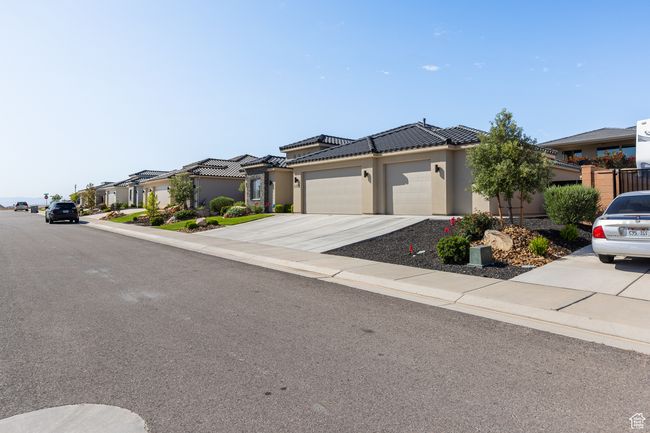 View of front facade with an attached garage, stucco siding, driveway, a residential view, and a tile roof | Image 64