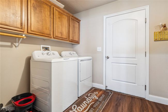 Laundry area featuring washer and clothes dryer, cabinet space, dark wood-style flooring, and baseboards | Image 20