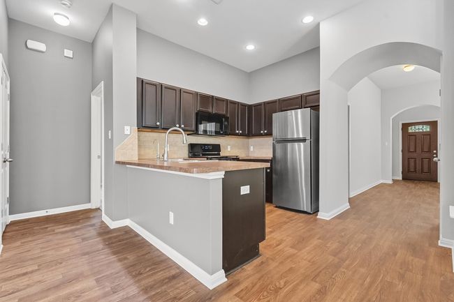 Kitchen featuring backsplash, light countertops, and dark wood cabinets | Image 8