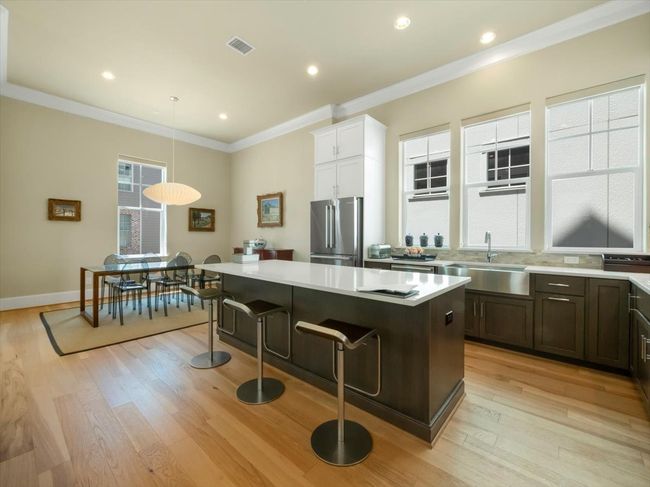 Kitchen featuring a sink, freestanding refrigerator, a kitchen island, light wood-type flooring, and light countertops | Image 5