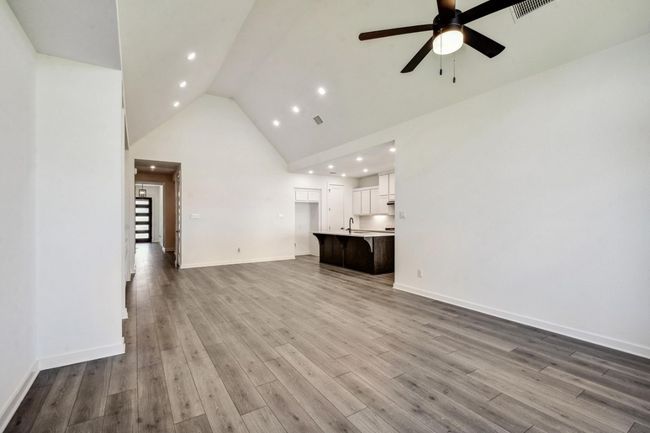 Unfurnished living room with a ceiling fan, high vaulted ceiling, recessed lighting, and wood finished floors | Image 12